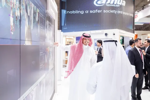 A participant at Intersec Saudi Arabia 2024 discussing smart cities technology on a digital display with another attendee, with a focus on advanced security solutions and smart cities development.